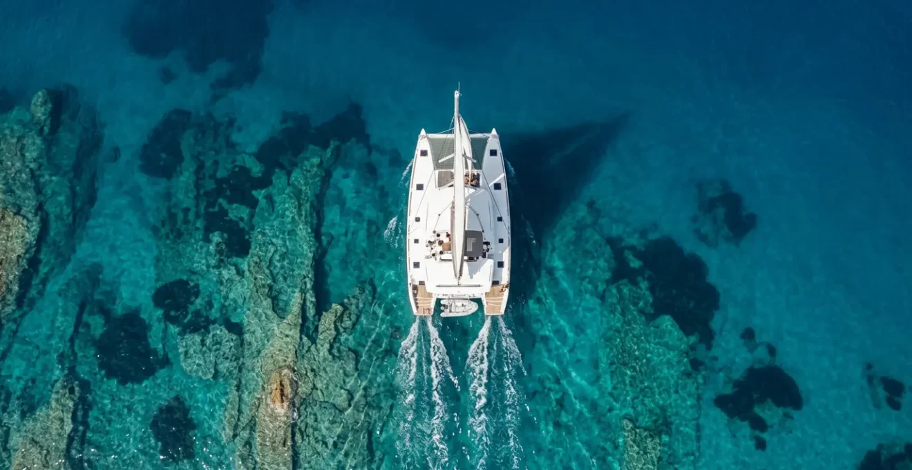 Vue aérienne d'un catamaran blanc naviguant sur les eaux turquoise de la mer Égée en Grèce