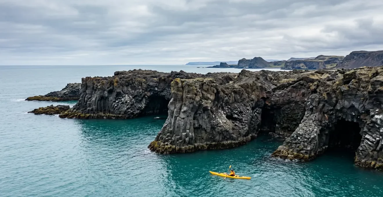 Kayakiste naviguant le long de formations géologiques spectaculaires d'une côte volcanique inaccessible par voie terrestre